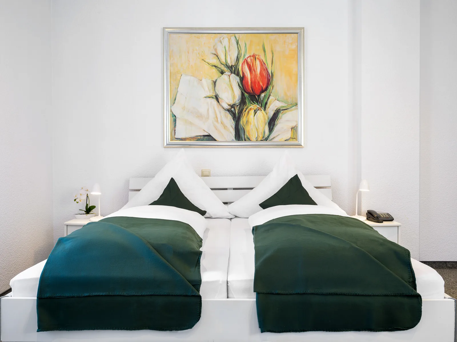 Doppelbett mit grünen Tagesdecken und Blumenbild im Hotel Jägerhof Herne
