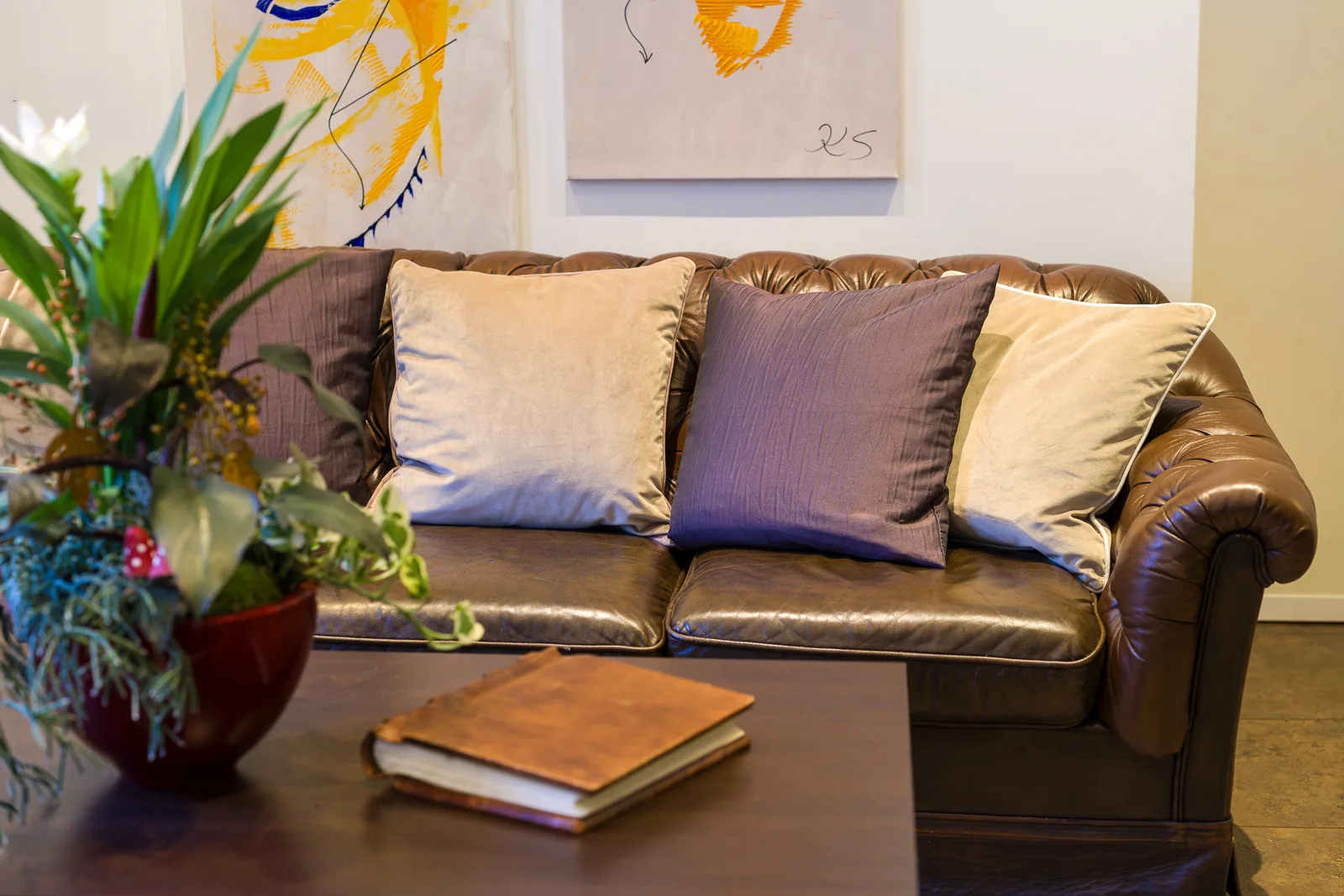 Gemütlicher Sitzbereich mit Ledersofa und Blumen in der Lobby des Hotel Jägerhof Herne